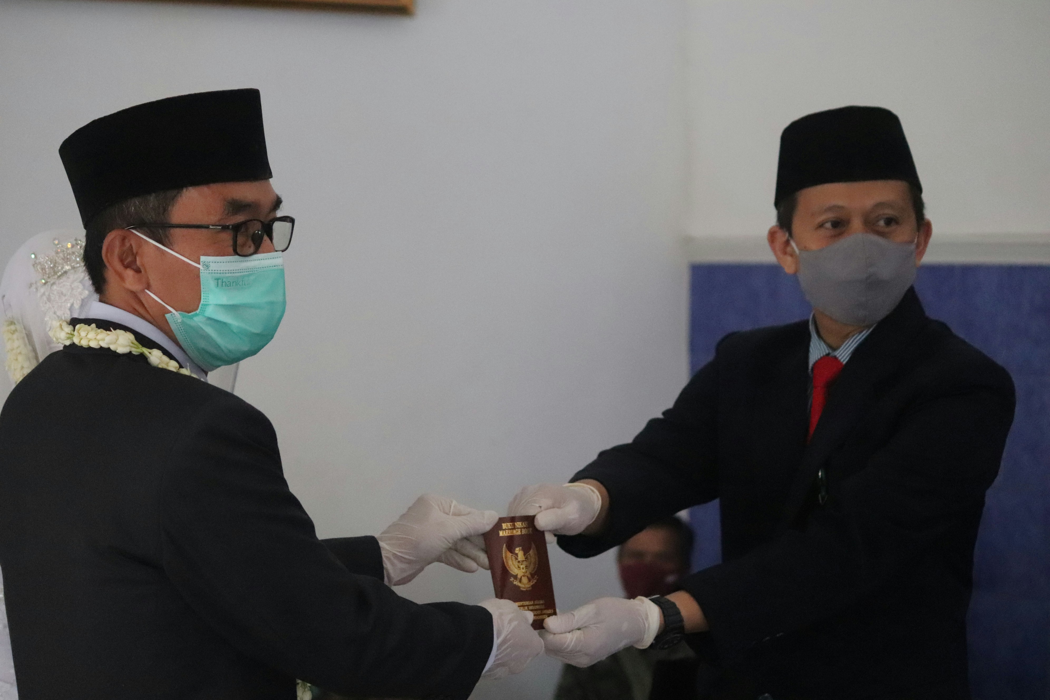 The head of the religious affairs office, Ajibarang, uses a mask and gloves to prevent Covid-19